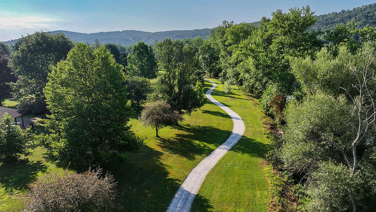 An aerial view of a path surrounded by green grass and trees