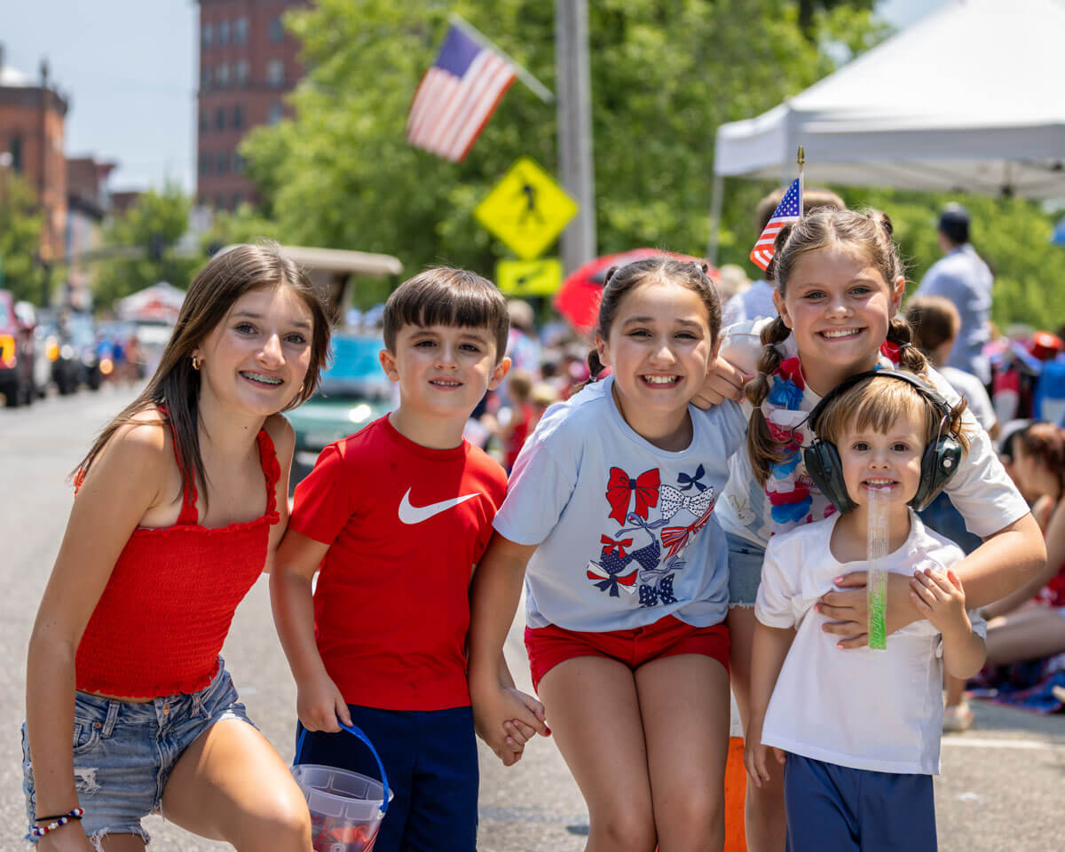 A group of 5 kids together smiling in red, white and blue clothes.