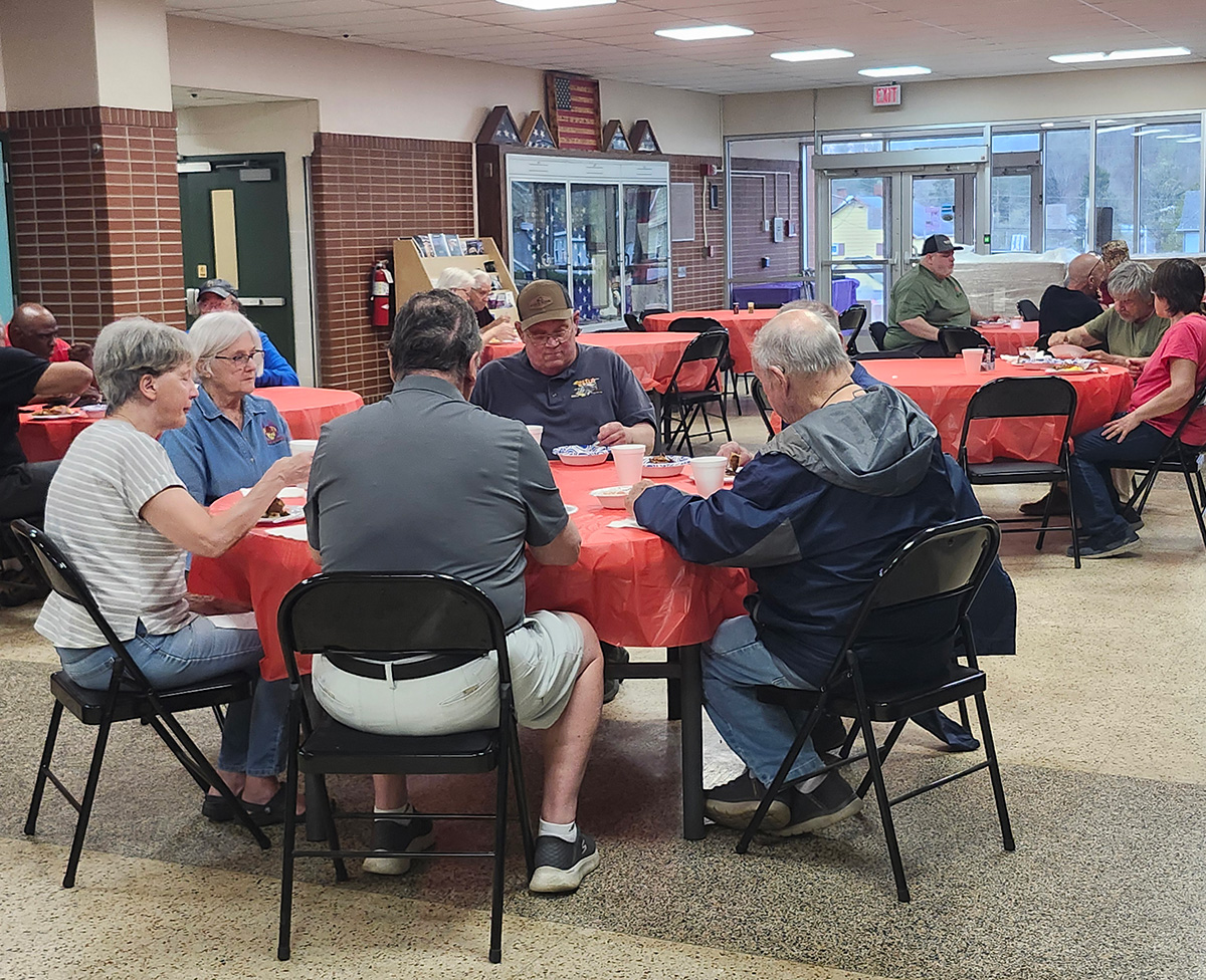 Community members gathered around tables sharing a meal at a Bee Courageous @ Garden Grub event in Warren County.